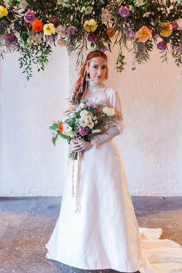 Bride holding bouquet under hanging floral arrangement