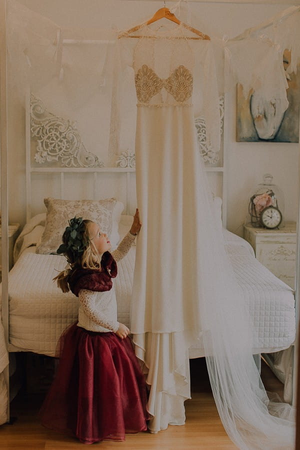 Flower girl looking at hanging wedding dress