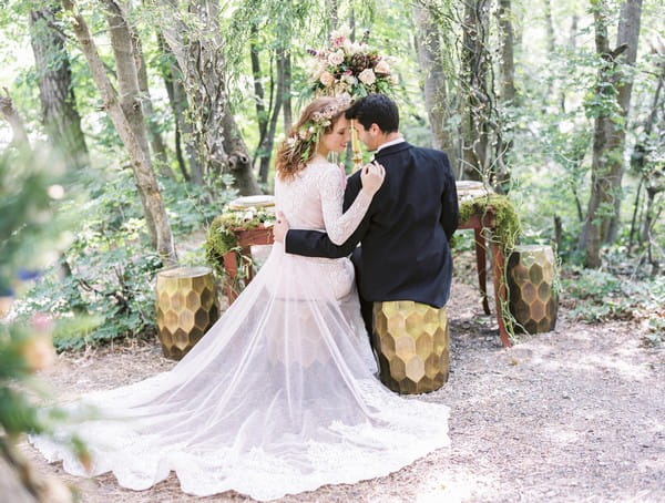 Bride and groom sitting at wedding table in woodland setting for A Midsummer Night's Dream wedding shoot