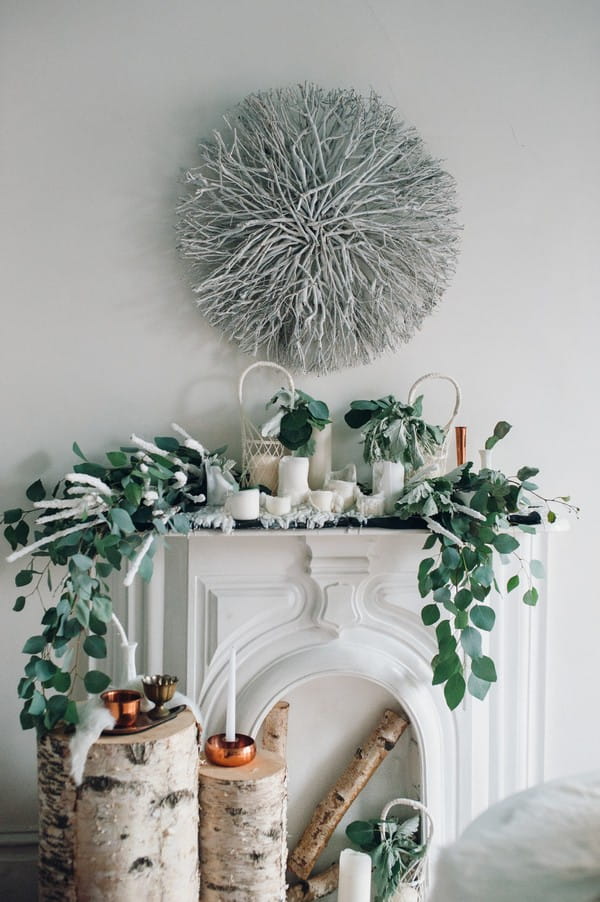 White mantelpiece decorated with foliage and candles