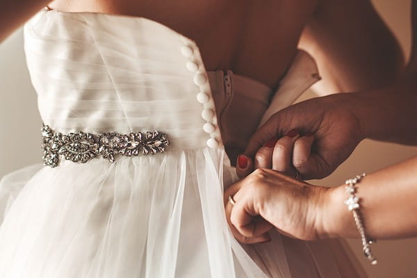 Fastening back of bride's wedding dress
