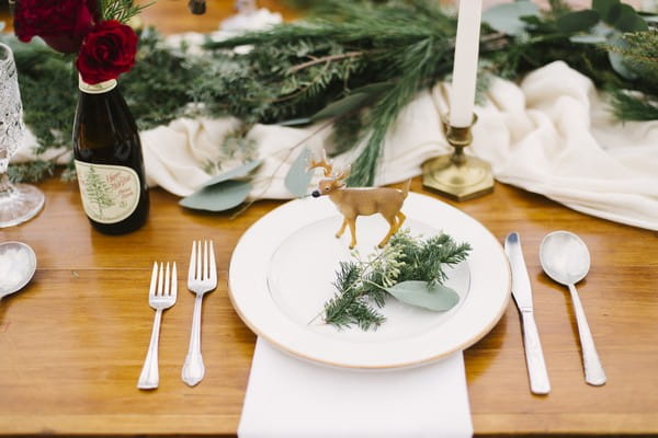 Deer and sprig of Christmas tree on plate at wedding place setting