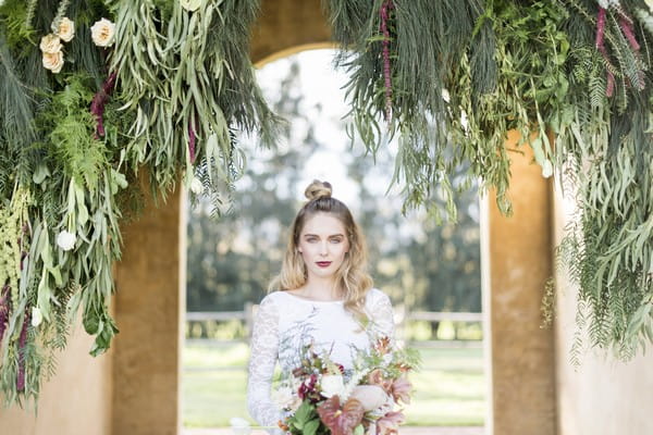 Bride standing under hanging foliage display