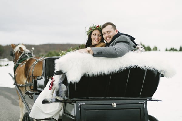 Bride and groom sitting in back of horse and cart carriage