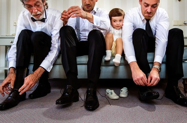 Pageboy being squashed between groomsmen tying their shoes - Picture by Virginia Gimeno