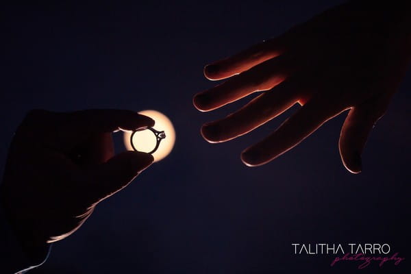 Moon shining behind wedding ring about to be put on finger - Picture by Talitha Tarro