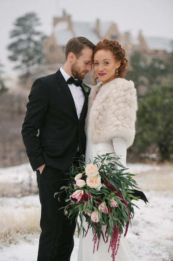 Bride holding winter wedding bouquet with groom
