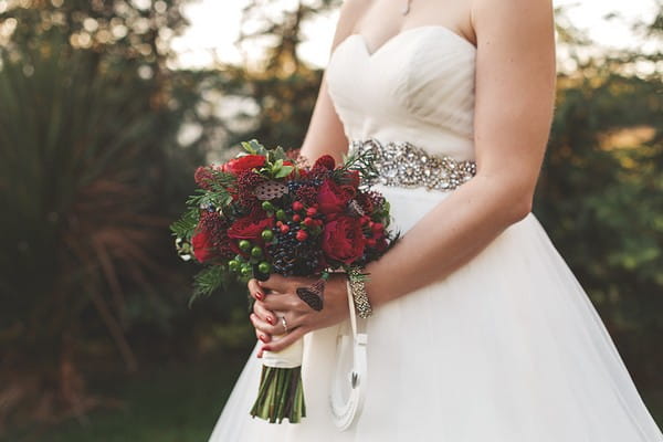 Bride holding red Christmas style bouquet
