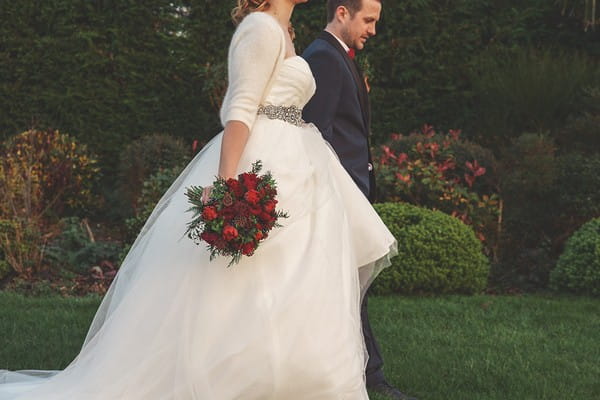 Bride walking holding bouquet by side