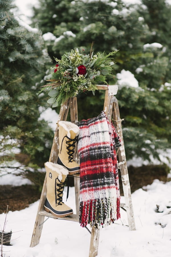 Winter boots, blanket and bouquet on ladder