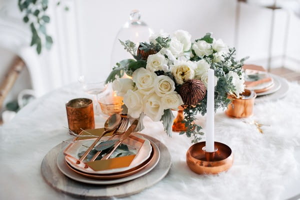 Copper wedding table decorations on white fur tablecloth