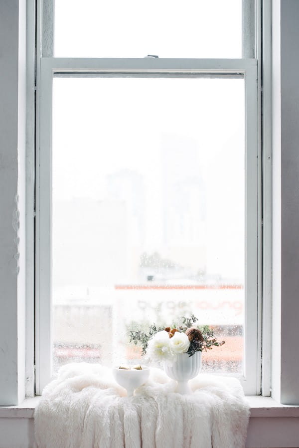 White vase of flowers on window ledge