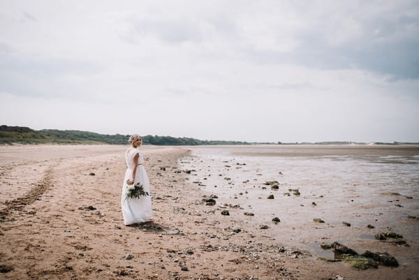 Bride walking on beach in Cumbria