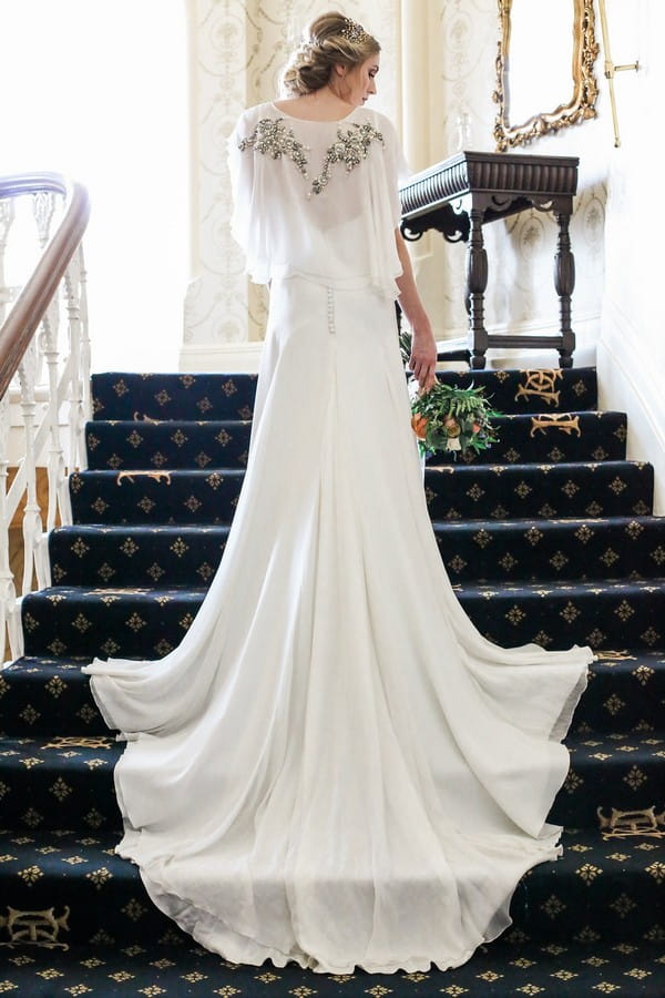 Bride standing on stairs with dress flowing down steps