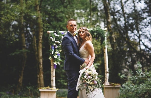 Bride and groom in woodland with wedding arch