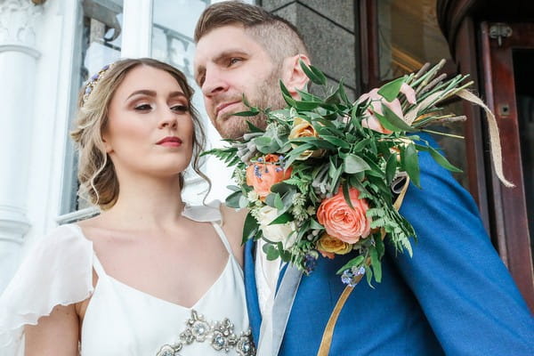 Bride holding bouquet with arm around groom's shoulder