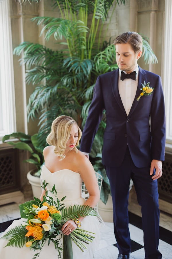 Groom standing next to bride sitting on chair