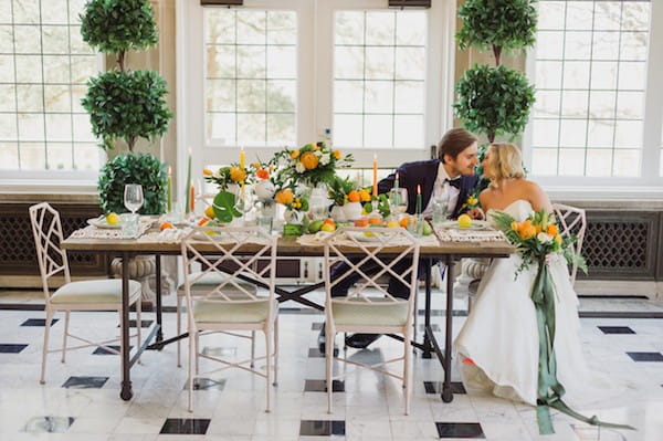 Bride and groom sitting at wedding table with citrus wedding styling