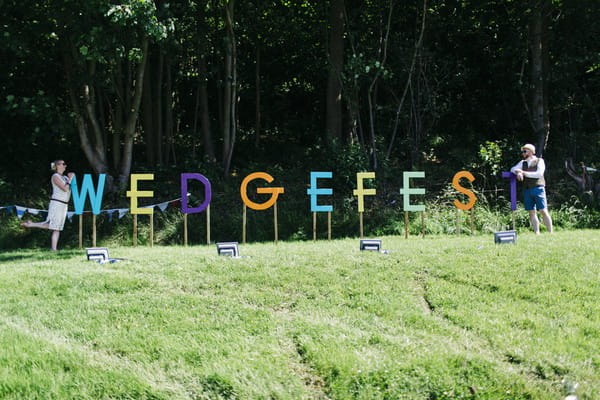 Bride and groom at either end of Wedgefest sign