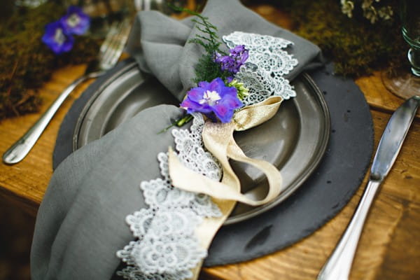 Dark styled wedding place setting with purple flower