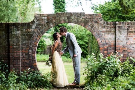 Bride and groom kissing in circular hole in wall - Picture by Nicola Norton Photography