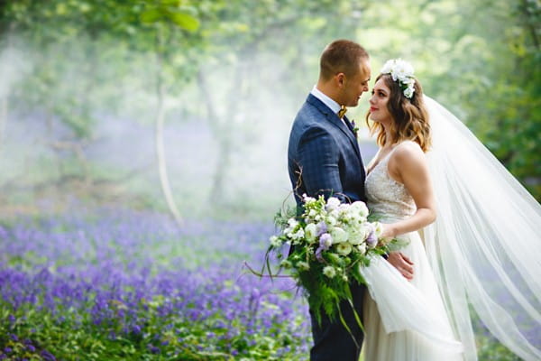 Bride and groom next to bluebells