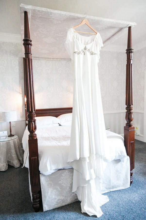 Wedding dress hanging from four poster bed