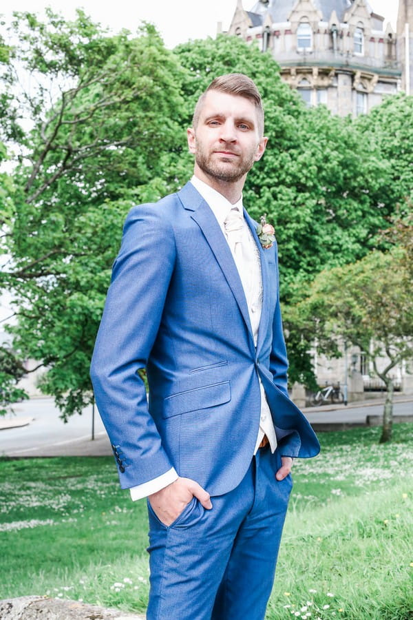 Groom in blue suit with hands in pockets