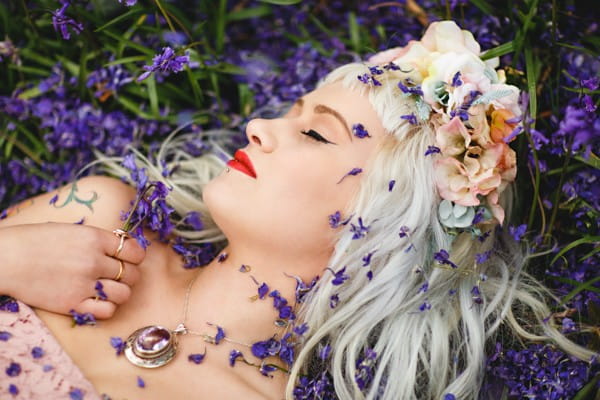 Bride laying on ground covered in purple confetti