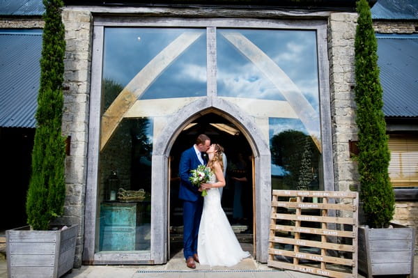 Bride and groom kissing at entrance of Cripps Barn