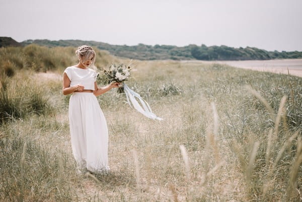 Bride walking on grass by beach