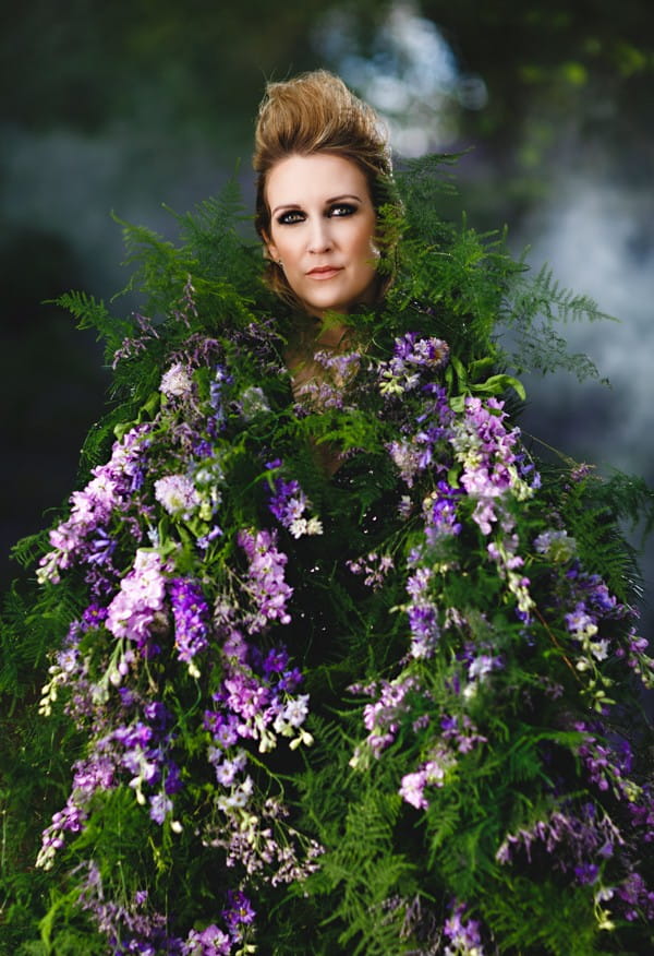 Bride wearing living cape of purple flowers and foliage
