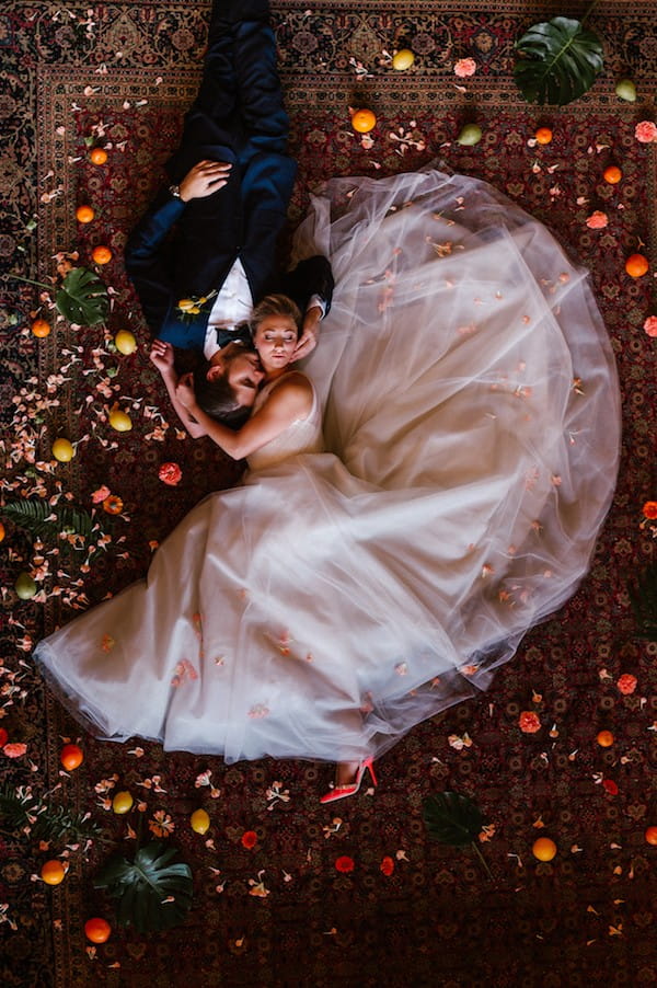 Bride and groom laying on floor surrounded by citrus fruit