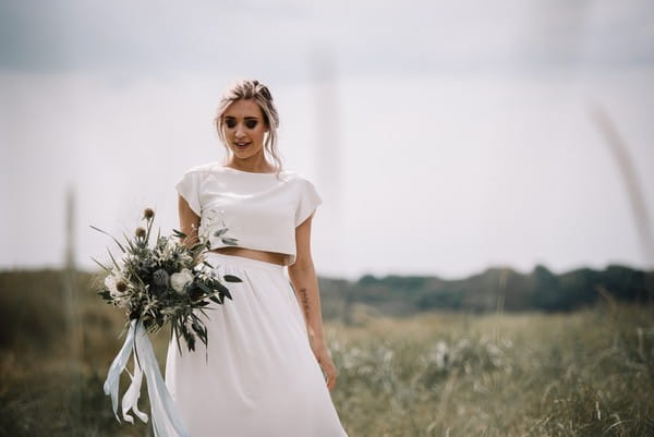 Bride wearing bridal separates holding bouquet