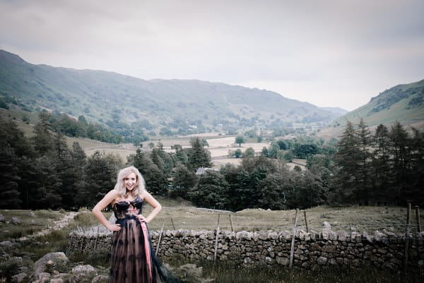 Bride with hands on hips in front of view of Lake District