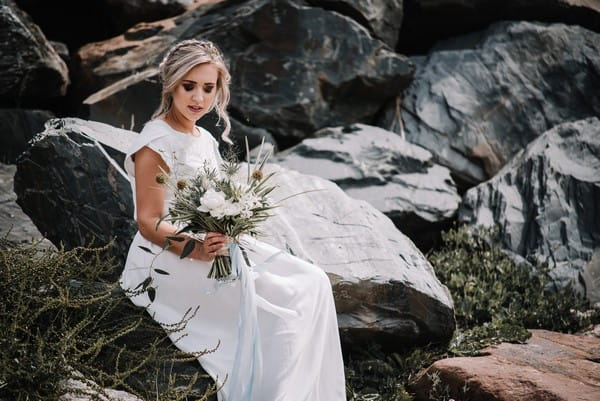 Bride sitting on rocks