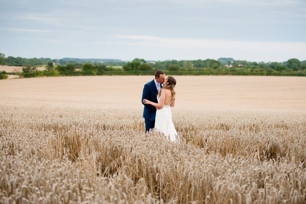 Bride and groom kissing in wheat field
