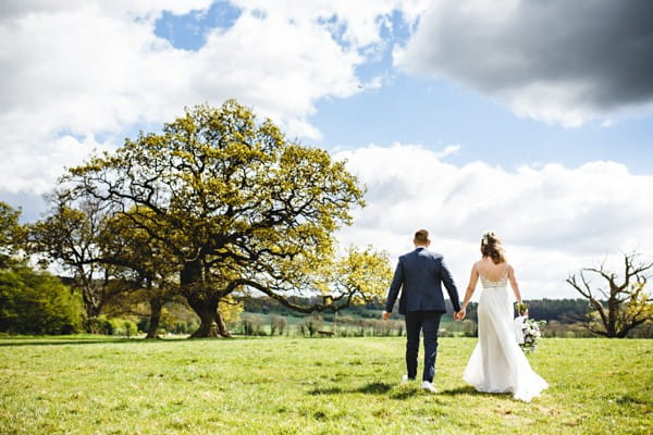 Bride and groom walking across field