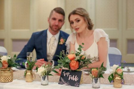 Bride and groom sitting at table with blush, copper and gold wedding styling