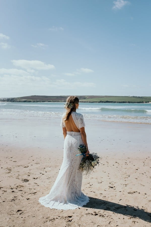 Bride with open back wedding dress looking at sea