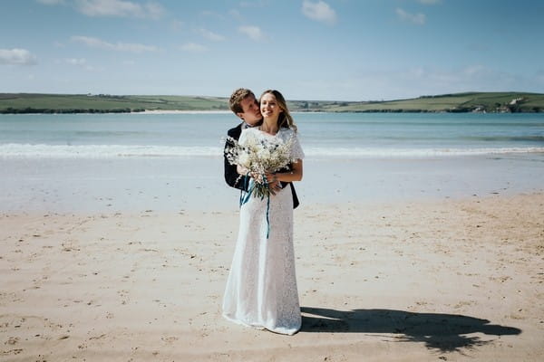 Groom behind bride with arms around her waist