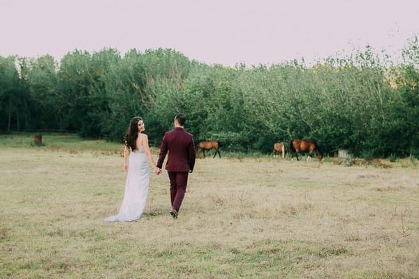 Bride and groom walking across field at Natte Valleij wedding