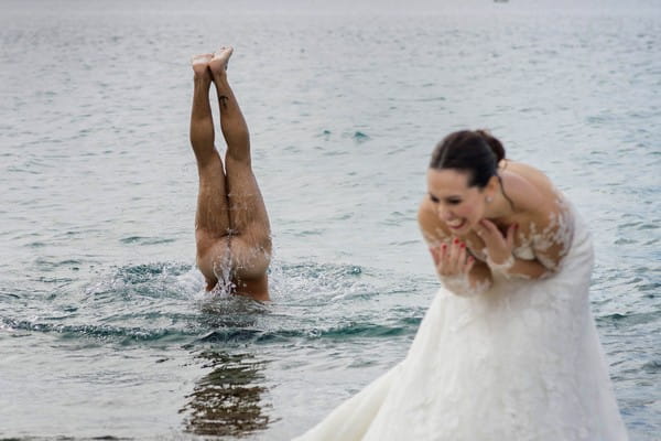 Bride laughing as naked man dives into water behind her - Picture by Photo-4U Pasquale Minniti