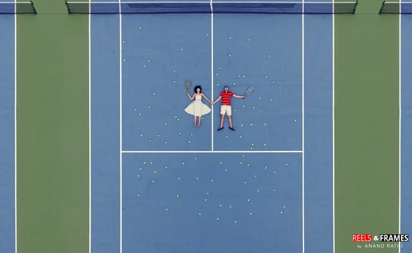 Aerial shot of bride and groom laying down on tennis court - Picture by Reels and Frames
