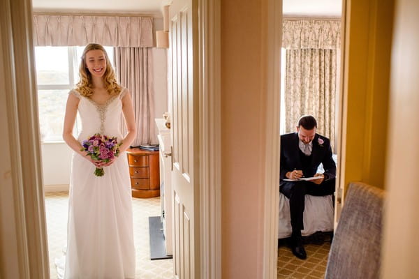 Bride stabding in one room as groom sits writing in the next - Picture by Stewart Girvan Photography