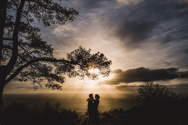 Bride and groom with arms around each other as sun shines through clouds - Picture by Murray Clarke