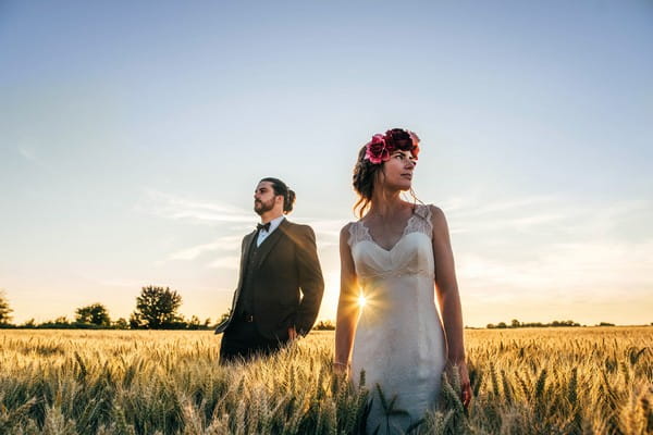 Bride and groom standing in field looking away from each other - Picture by Three Flowers Photography
