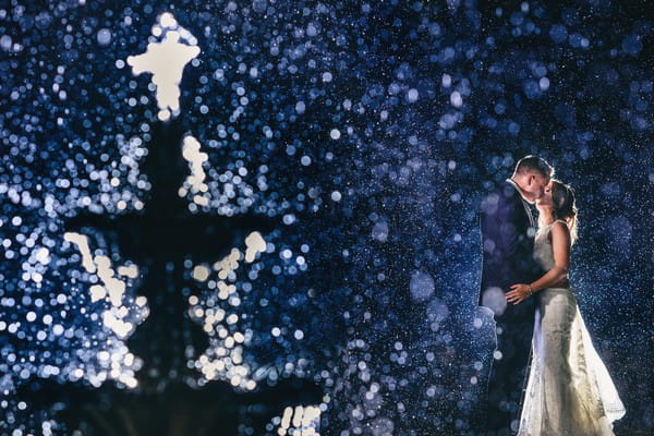 Bride and groom kissing behind spray of water fountain - Picture by Ash Davenport of Miki Studios