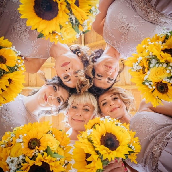 Bridesmaids looking down at camera with sunflowers