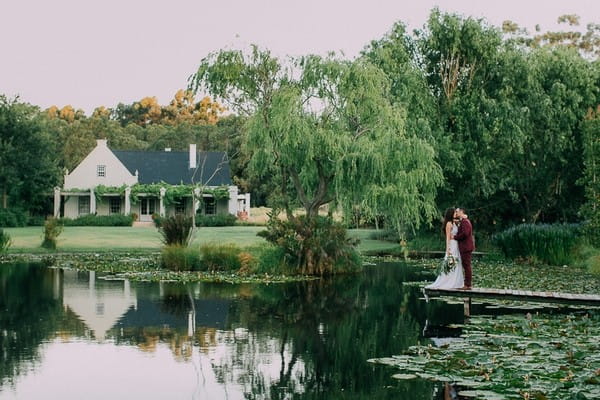 Bride and groom kissing by lake at Natte Valleij wedding